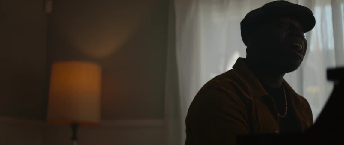 A young black man is singing inside of his home
