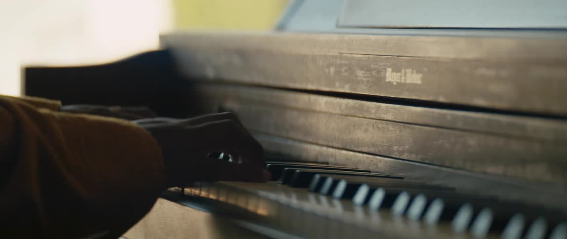Person playing keys on an old wooden piano