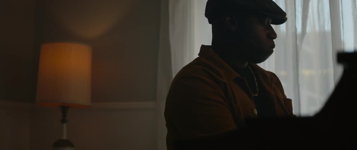 A man playing piano with his eyes closed in a living room