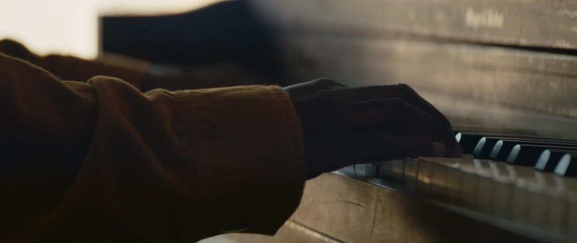 A black man is playing the piano inside the room