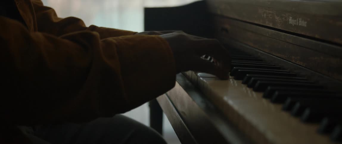 A person is sitting and playing the piano indoors