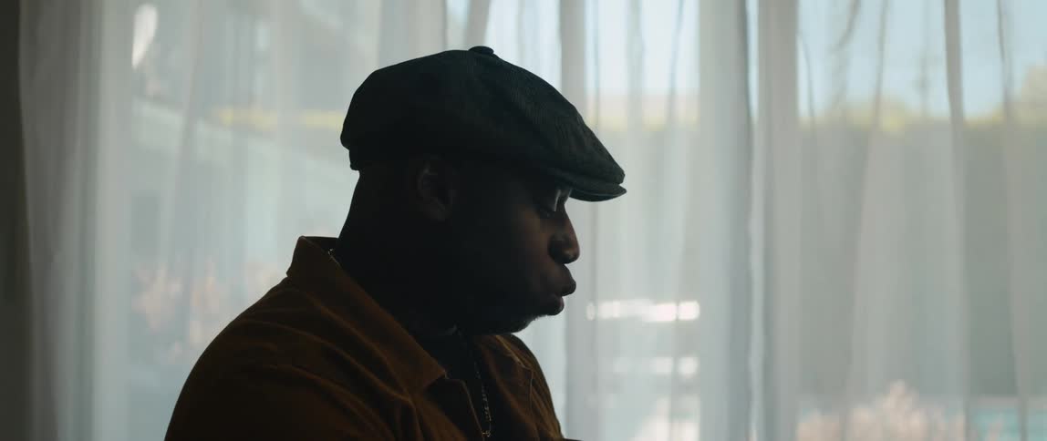 A black man is in his room singing in the day time