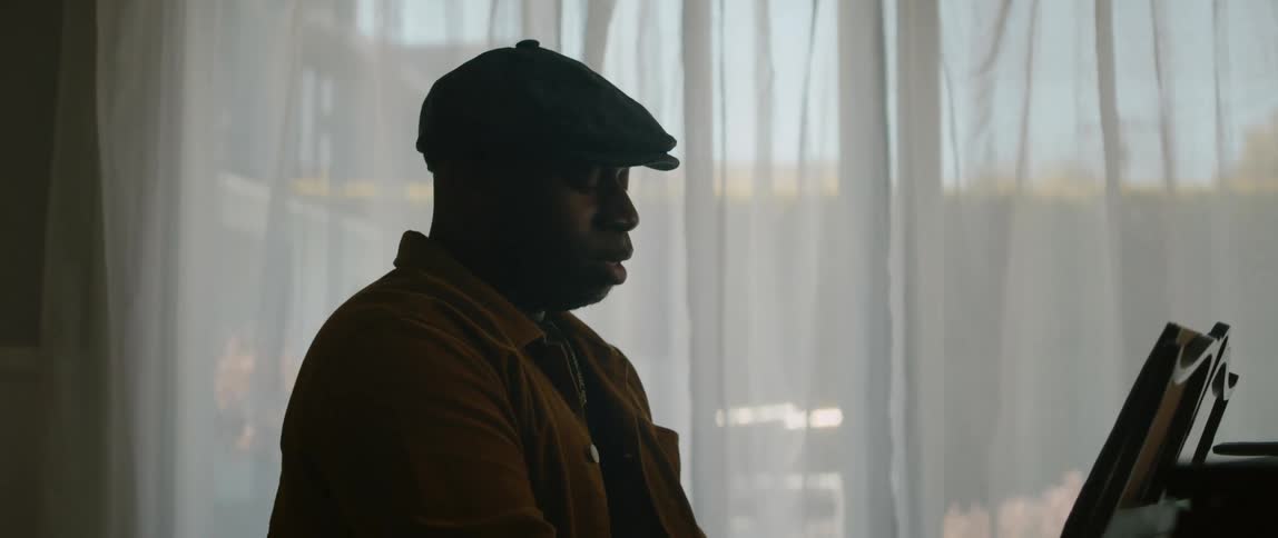 A young black man is playing the piano and singing