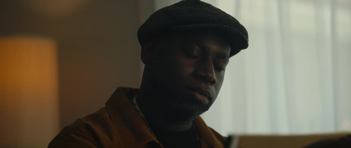 A young black man is sitting down in the living room
