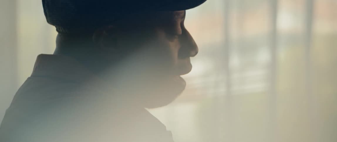 A man is sitting in his house next to a window at sunset