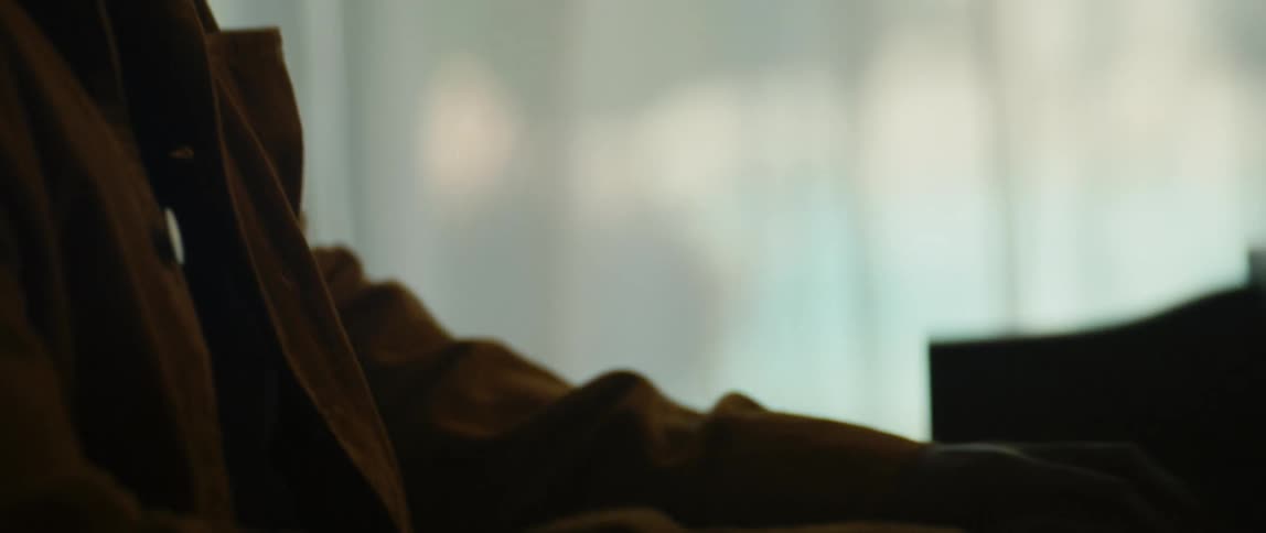 A man is playing the piano by a window indoors