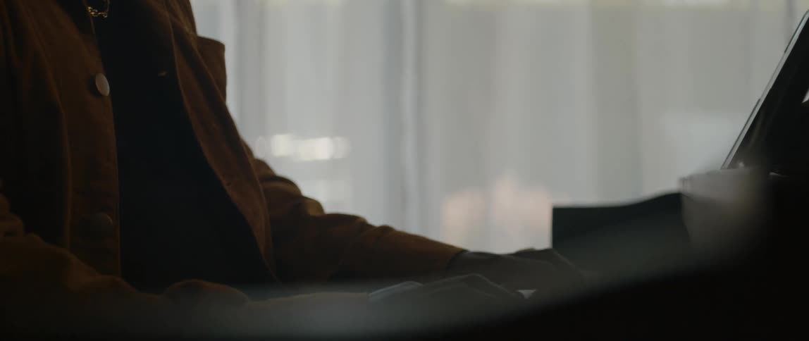 A young black man is singing and playing the piano