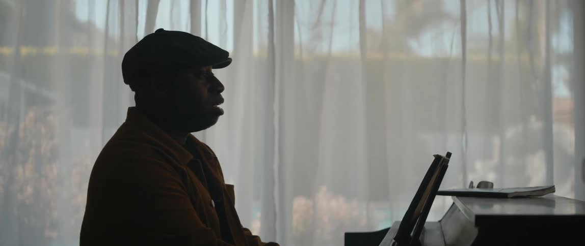 Silhouette of a man playing the piano inside a dimly lit room on a house