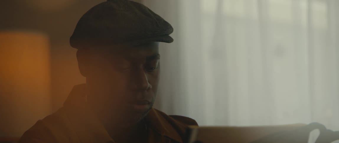 A black man is in the living room playing music