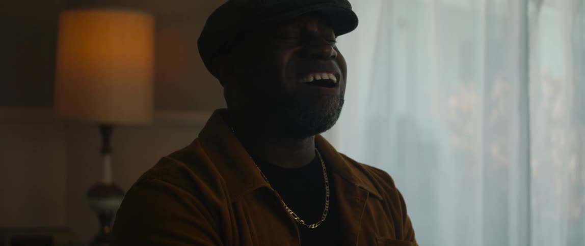 A man sits at a piano and sings as he smiles