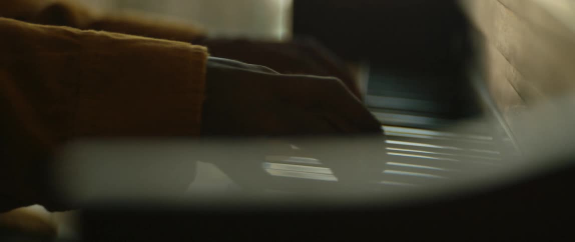 Man with orange blazer jacket plays piano in room