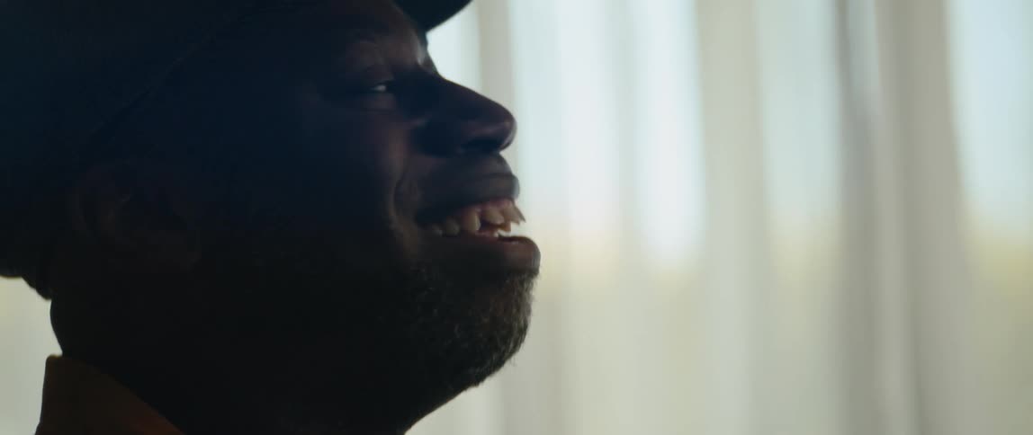 A man is sitting indoors and is smiling