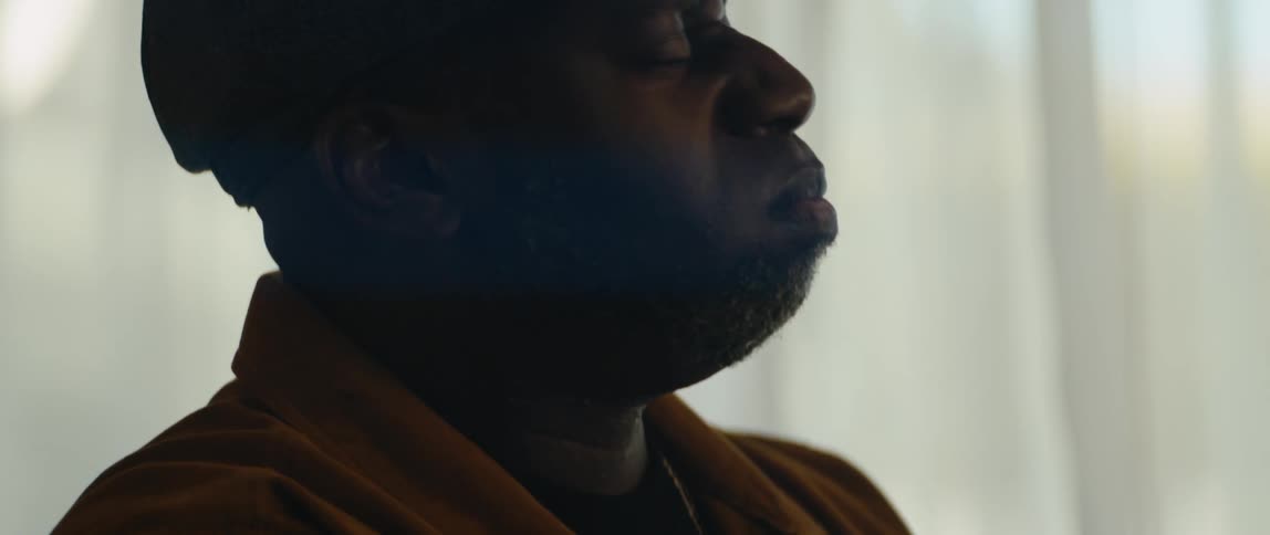 A young black man is sitting down in the room