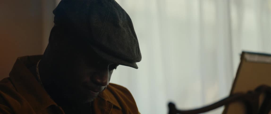 Silhouette of a man playing the piano inside a dimly lit room on a house