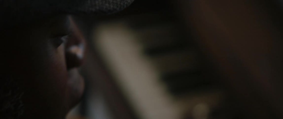 A young black man is playing the piano inside his house