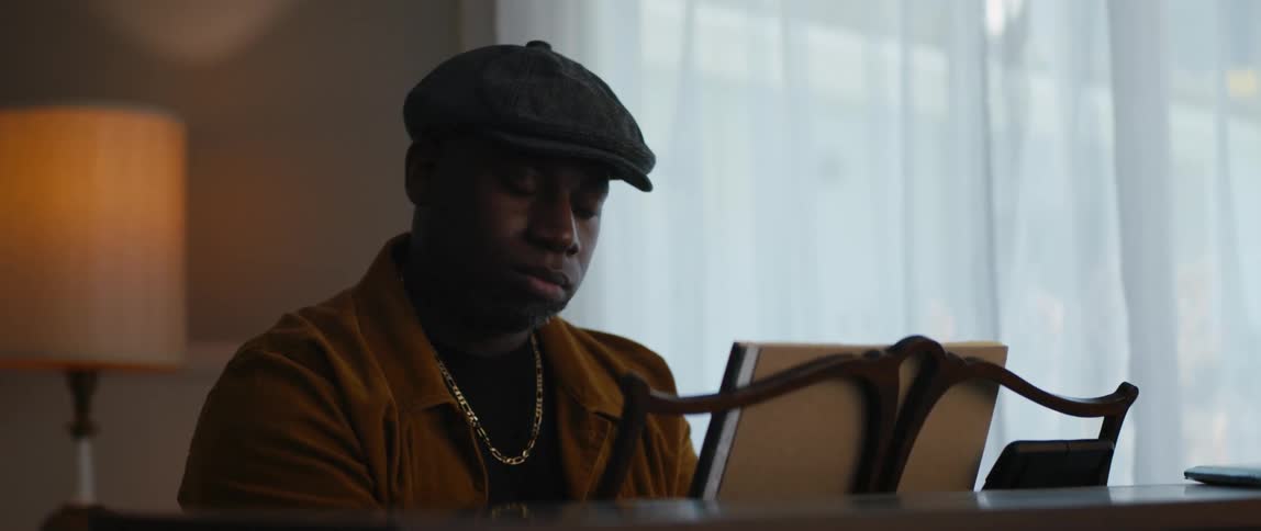 A black man is playing the piano in the living room
