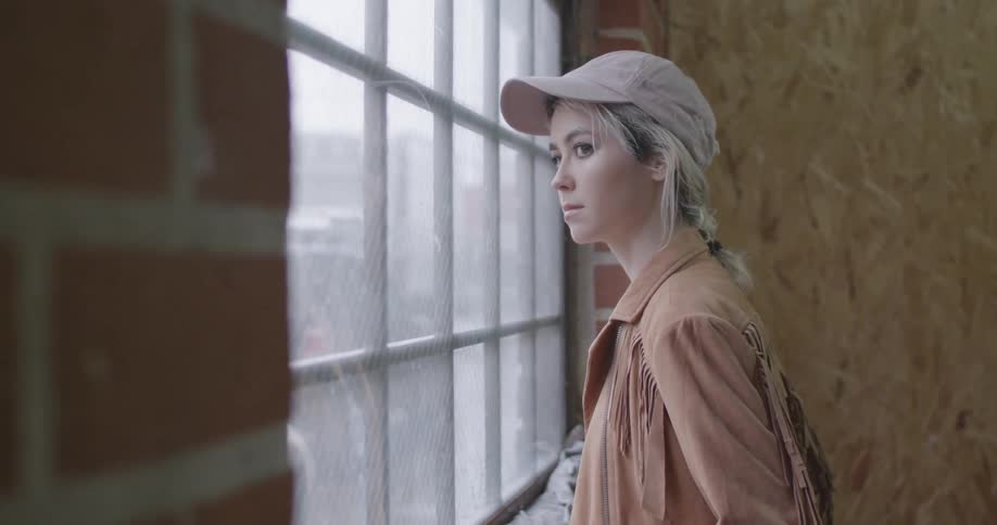 A woman walks over to a window looking out