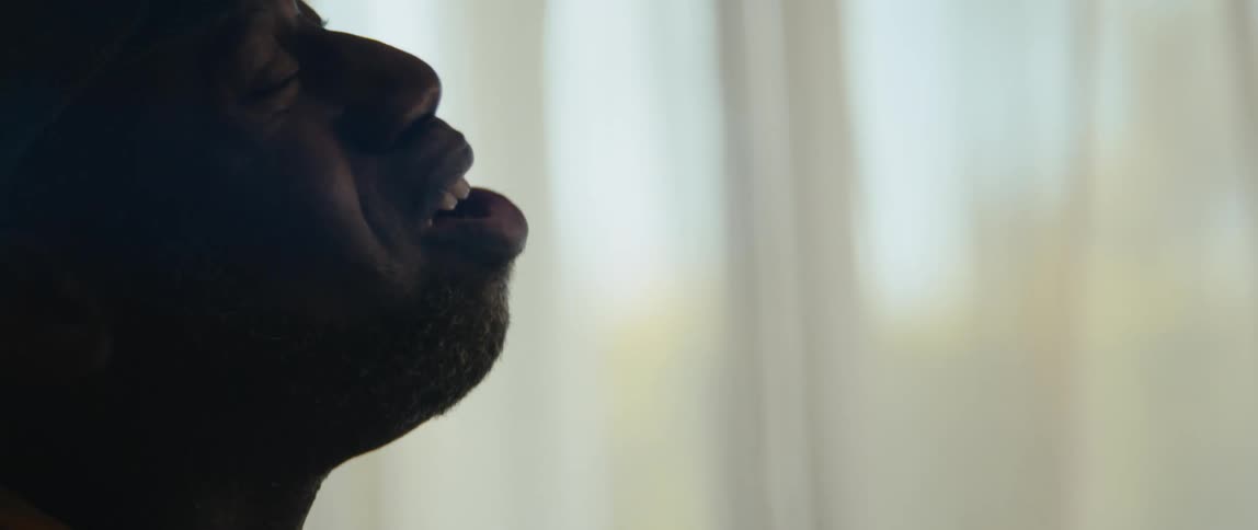 A young black man is singing inside of his house