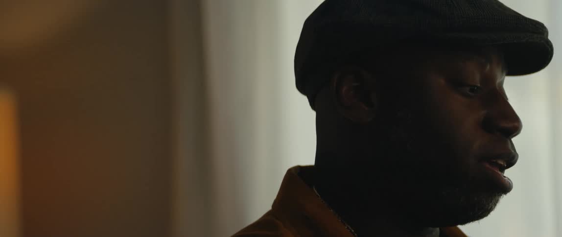 A man is wearing a hat and singing near a window