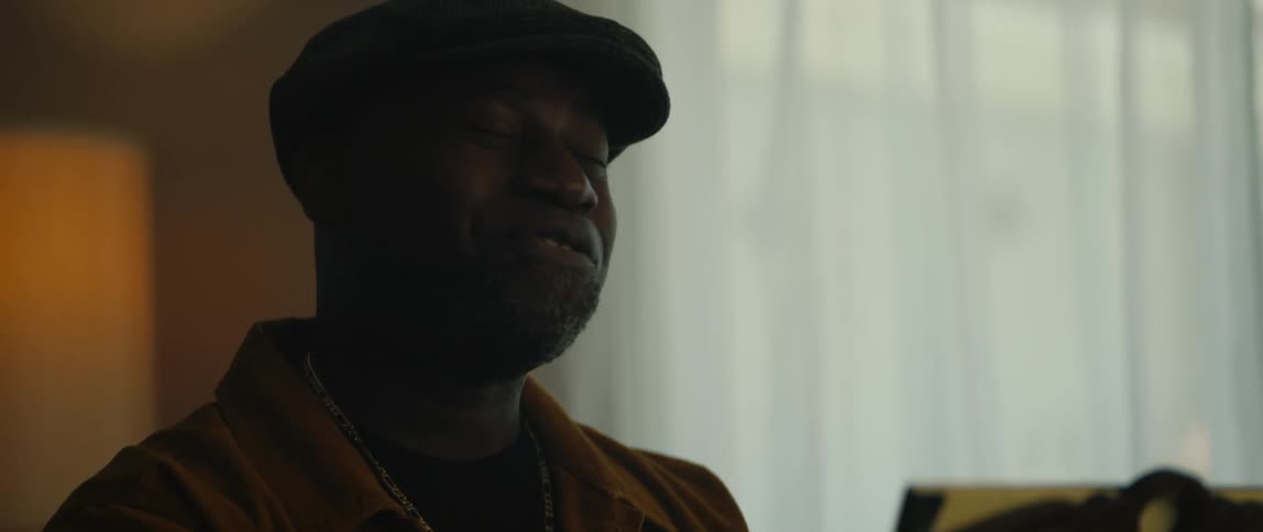 A man is singing and sitting near a window