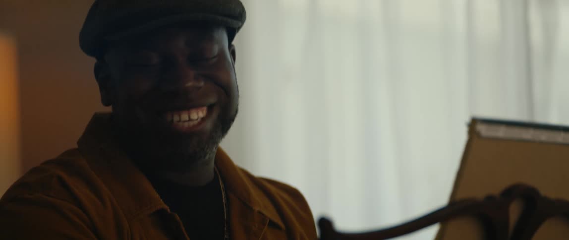 A man is sitting indoors and looks happy