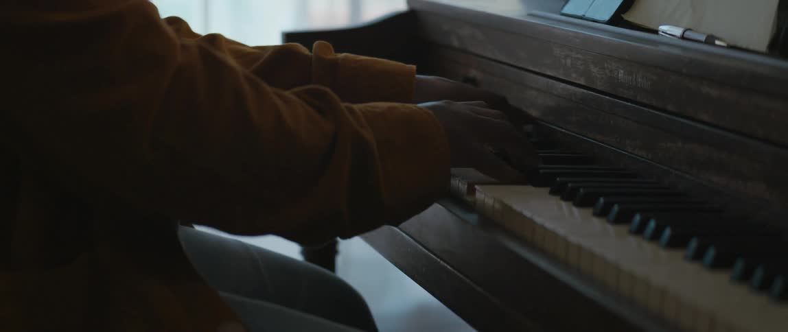 A young black man is playing the piano inside his house