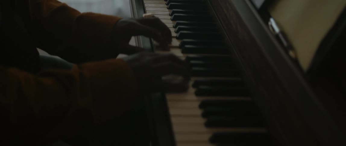 Man playing the piano inside a dimly lit room on a house