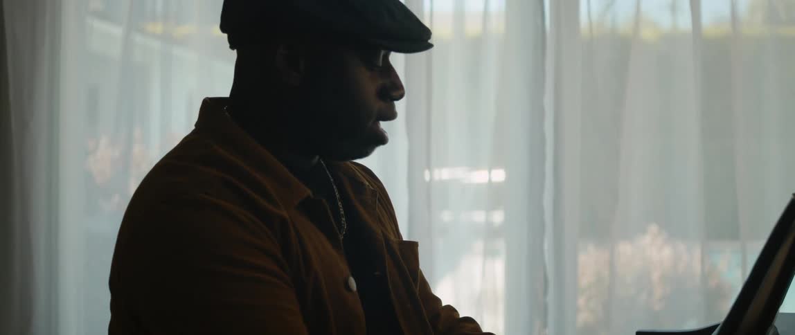 A young black man is playing the piano and singing