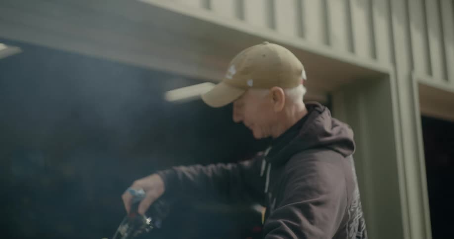 White smoke comes out of the exhaust of a motorcycle being throttled outside a garage