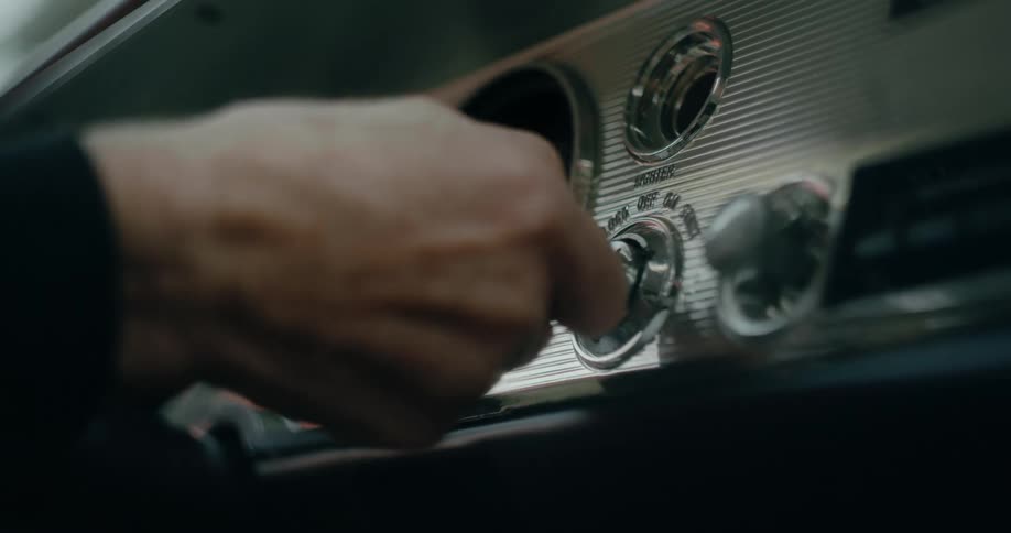 Man putting key into a car and starting the engine