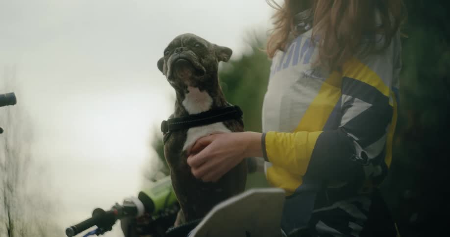 A woman pets her dog by her bike