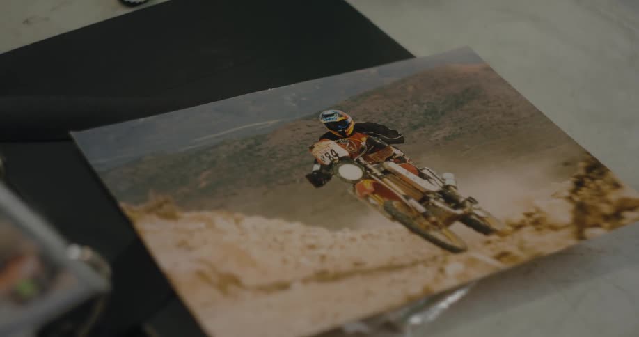 A photograph of a motorcycle racer sitting on an album