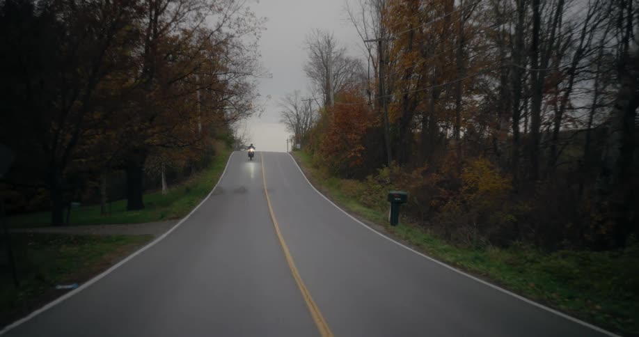 A person riding a motorcycle is coming down a lonely road