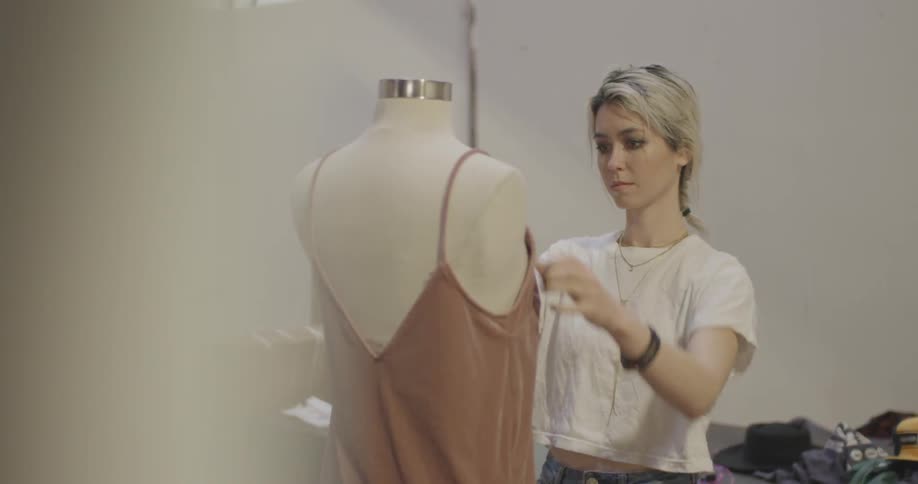 A woman is trying a dress on a mannequin