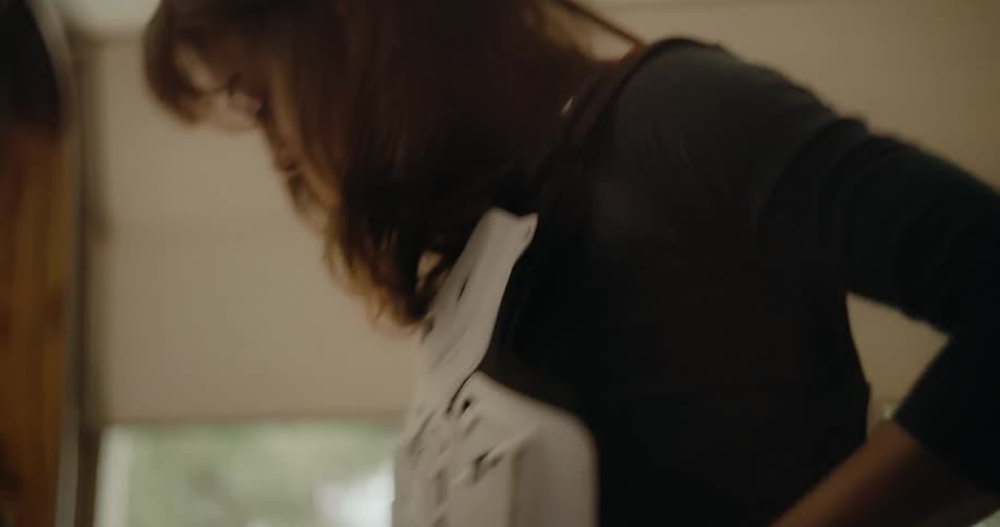 A woman puts football pads on over a shirt