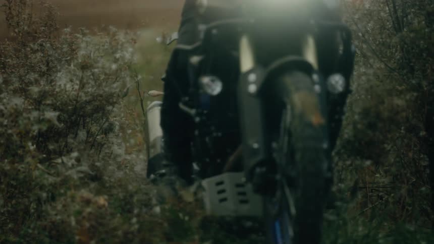 A person is driving a motorcycle through the wilderness
