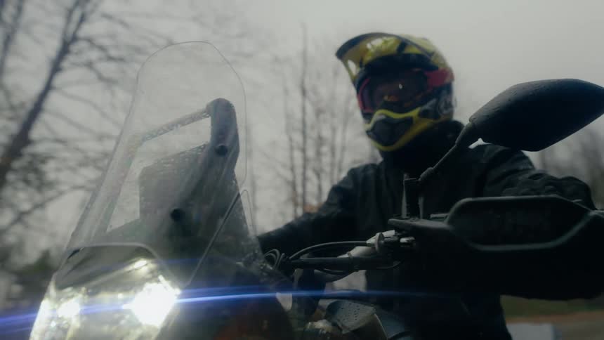 A man is sitting on a parked motorcycle in winter