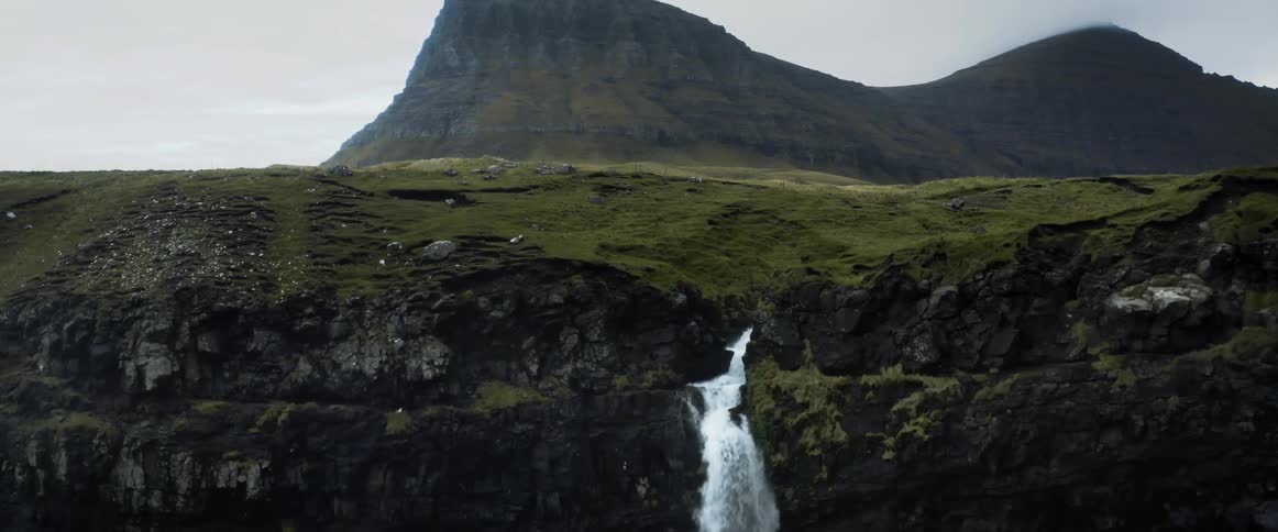 Aerial view of a waterfall flowing down a cliff near a small town
