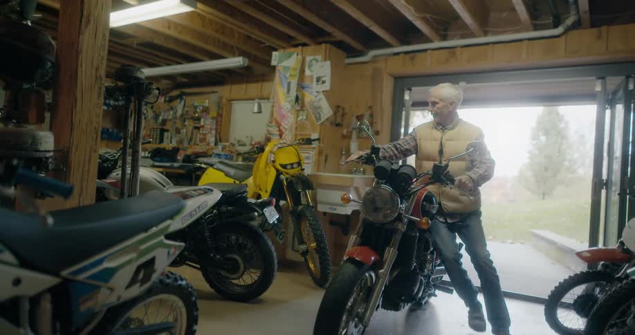 A man is moving his motorcycle out of a garage