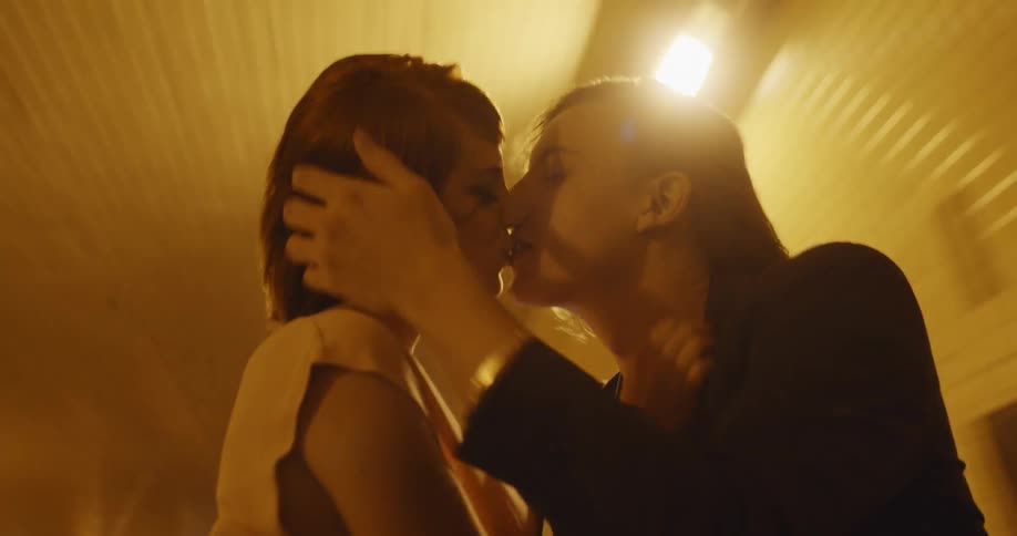 Young couple standing through the cars sunroof and making out while the car is driving through a tunnel at night
