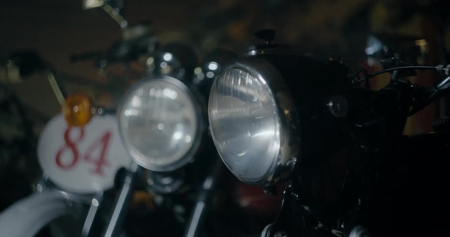 Group of vintage motorcycles parked inside a dimly lit garage
