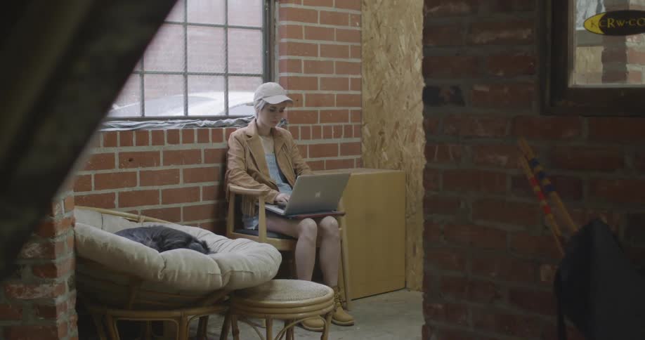 A woman uses a laptop while seated by a window