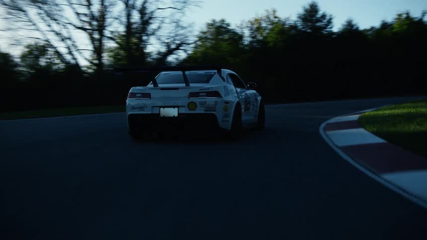A car is driving down the road in the middle of the day