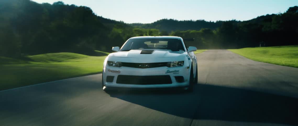 A person is driving a sports car on a road during spring