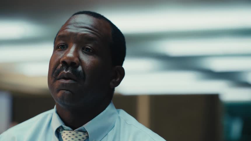 A man is wearing a suit and sitting in an office