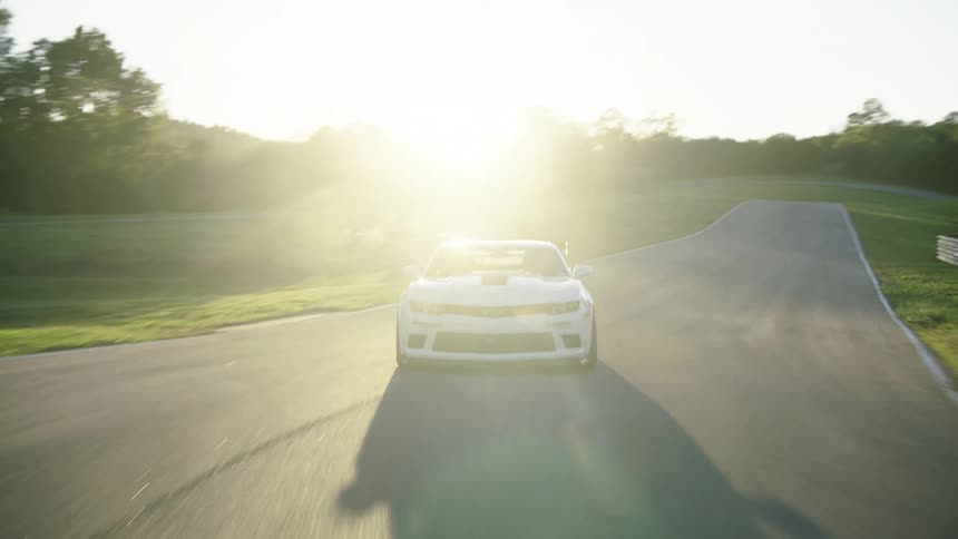A car is driving on a race track during the summer