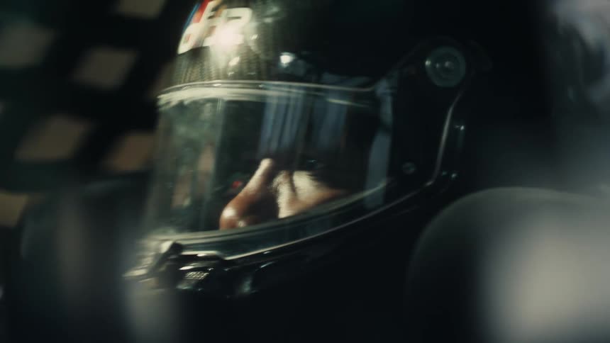 A race car driver in a crash helmet driving a car
