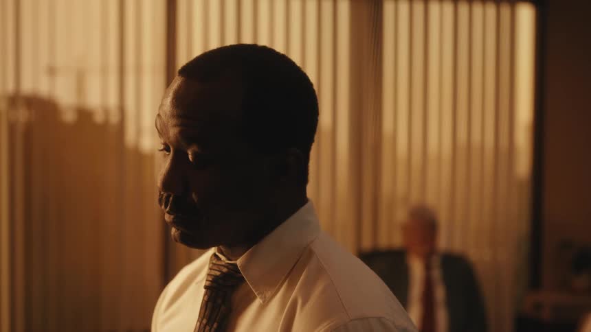 A man in a button up shirt and tie speaking indoors
