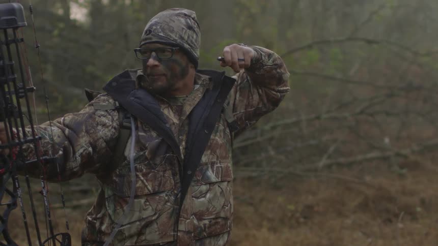 A man in camo fires a bow