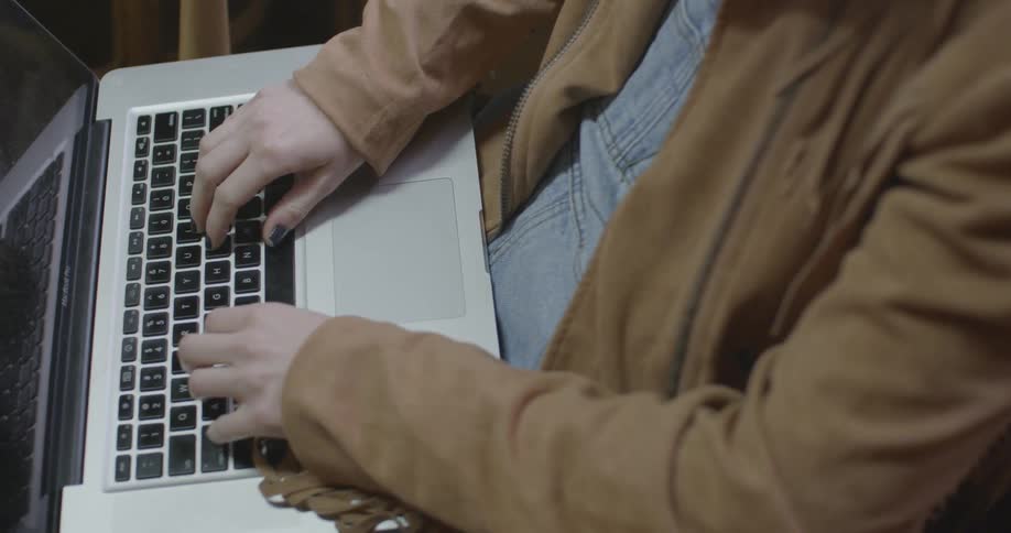 A person in a brown jacket uses a laptop